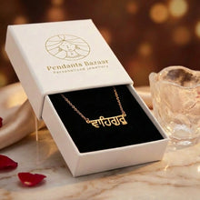 Charger l'image dans la galerie, Gold necklace with name pendant in a 'Pendants Bazaar' box on a decorative setting with rose petals and a glass candle.