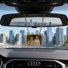 Charger l'image dans la galerie, Car interior with a gold chain hanging from the rearview mirror, featuring an image of two people, with a cityscape in the background.