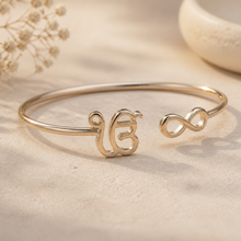 Charger l'image dans la galerie, Gold bracelet with infinity symbol on a beige background
