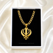 Load image into Gallery viewer, A gold-tone Khanda pendant necklace displayed inside a white jewelry box with a black insert, set against a cream satin fabric background. The brand name 'PENDANTS BAZAAR' is printed on the front of the box.
