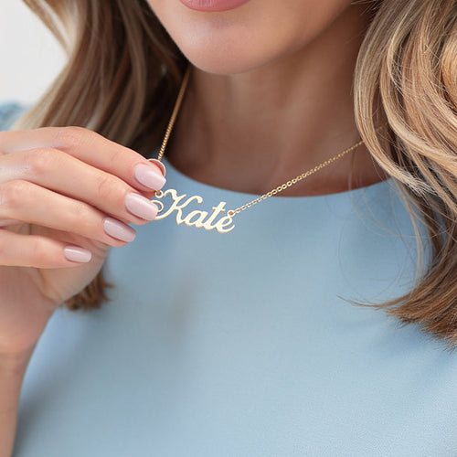 Woman wearing a gold necklace with 'Kate' pendant against a light background