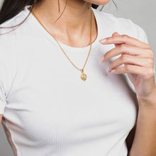 Charger l'image dans la galerie, Person wearing a gold necklace with a pendant on a plain background
