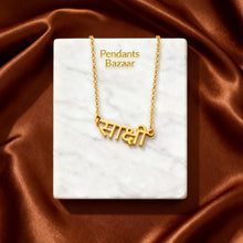 Charger l'image dans la galerie, Gold necklace with name pendant on a white card with 'Pendants Bazaar' text, against a brown satin background.

